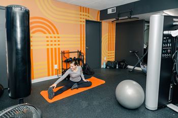 A woman is doing stretching exercises on an orange mat in a gym at Walnut Towers at Frick Park, Pittsburgh, Pennsylvania